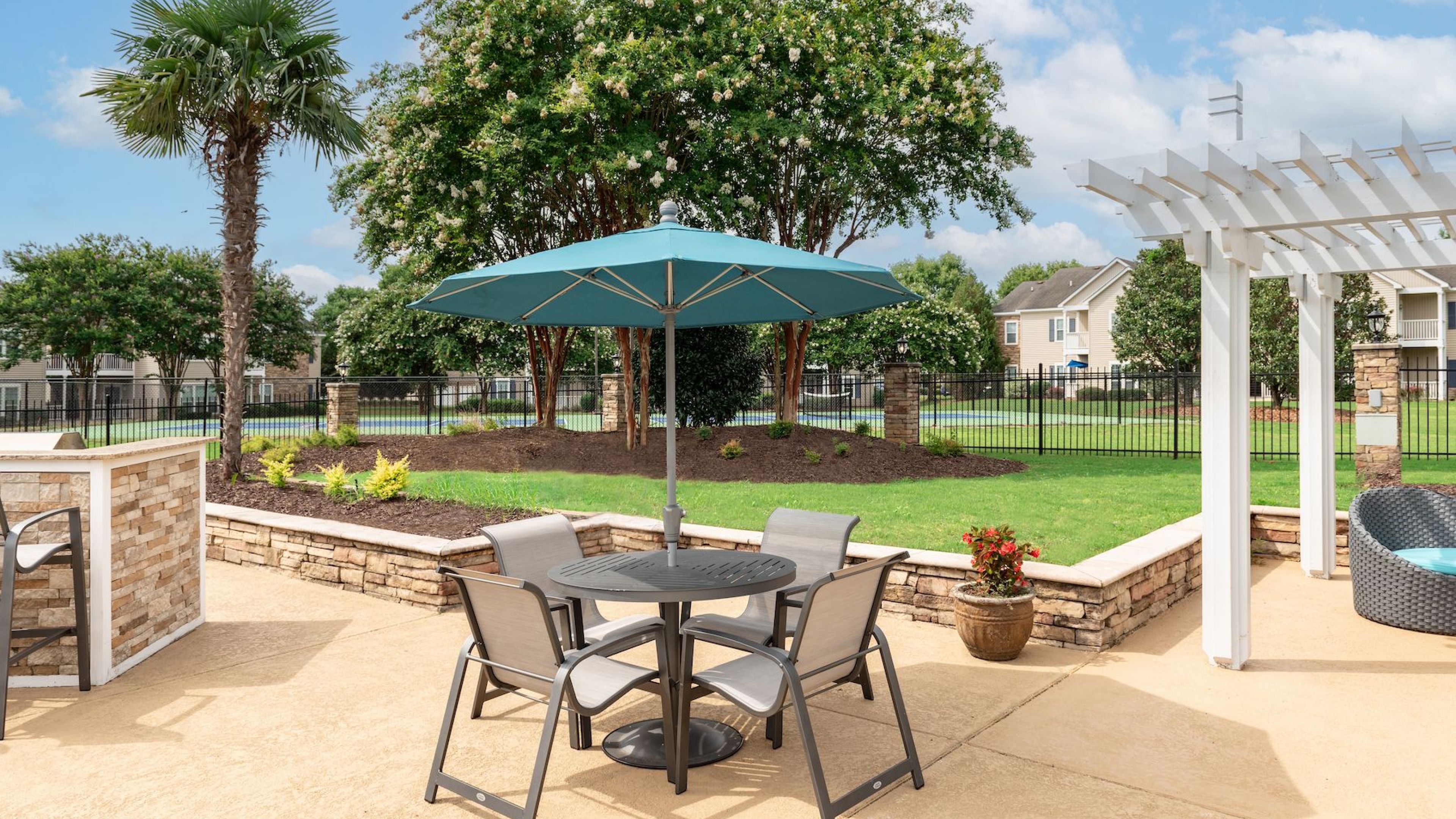 Outdoor patio with furniture and umbrella in the peaceful Hawthorne Meadowview complex in Warner Robins, GA